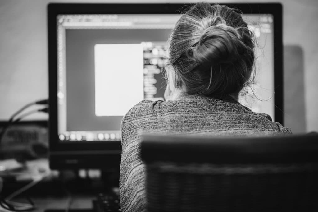 A young woman with a bun hairstyle is working from her computer.