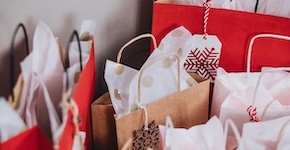 A stack of brown and red gift bags with lots of white tissue paper, all ready for the holidays.